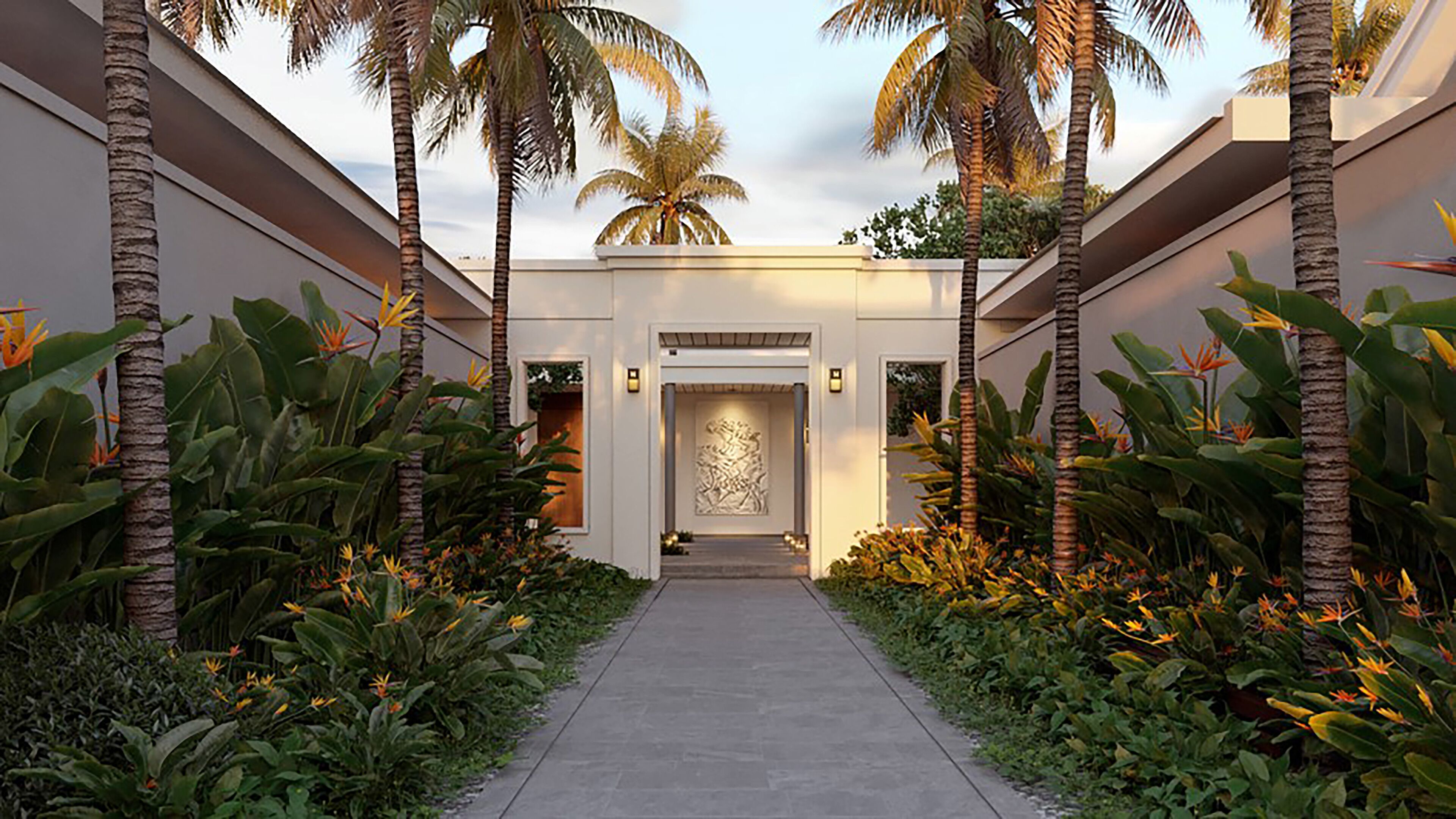 A pathway leading to a building entrance with palm trees and tropical plants on either side.