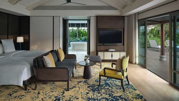 A hotel room with a bed, sofa, armchair, and a TV.