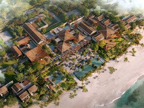 Vista aérea de un resort con varias construcciones, una piscina y una playa.