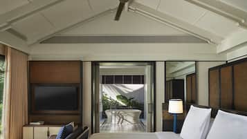 A hotel room with a bed, a TV, a ceiling fan, a bathroom with a bathtub, and a view of the outdoors.
