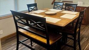 En spiseplads med et træbord, fire stole og en lampe i loftet.