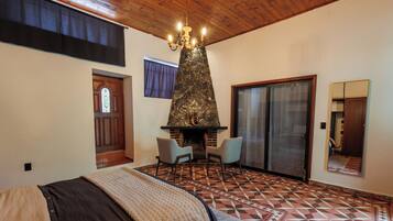 A bedroom with a bed, a fireplace, a large mirror, and a geometric patterned floor.