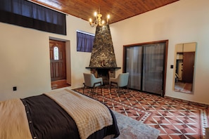 Un dormitorio con cama, chimenea, un espejo grande y un piso con diseño geométrico.