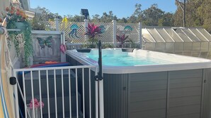 A hot tub with a ladder, surrounded by a white fence, and a pool in the background. - 2 BED BEACH HUT+ STUDIO+SWIMSPA,SAUNA,PATROLLED BEACH,TAVERN, SHOPS,RESTAURANTS. (Tannum Sands)
