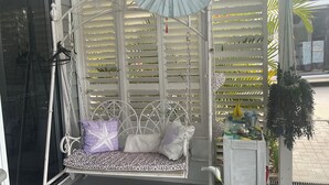 A white swing chair with patterned cushions and a hanging umbrella. - 2 BED BEACH HUT+ STUDIO+SWIMSPA,SAUNA,PATROLLED BEACH,TAVERN, SHOPS,RESTAURANTS. (Tannum Sands)