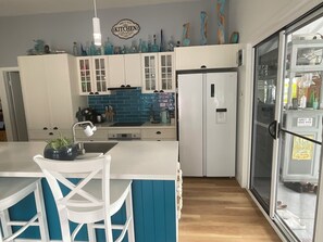 Eine Küche mit weißen Schränken, einer blauen Spritzschutzwand und einem Kühlschrank.