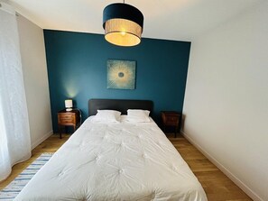 A bedroom with a large bed, a bedside table, a lamp, and a wall-mounted light fixture. - Beautiful family home with garden, terrace, wifi, near Guidel beach (GUIDEL)