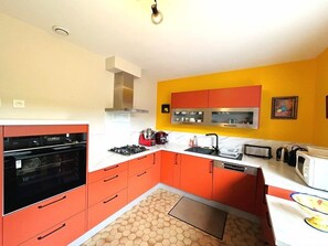 A kitchen with orange cabinets, a white countertop, a stainless steel range hood, and a microwave. - Beautiful family home with garden, terrace, wifi, near Guidel beach (GUIDEL)