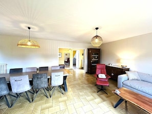 A modern living room with a dining area, a red chair, a sofa, and a wooden coffee table. - Beautiful family home with garden, terrace, wifi, near Guidel beach (GUIDEL)