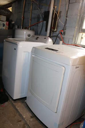 Two stacked white washing machines in a room with visible plumbing and a window. - 3-bedroom house in adorable College Park with AC (College Park)