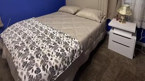 Ein Schlafzimmer mit einem Bett, einem Nachttisch mit Lampe und zwei gerahmten Bildern an der Wand.