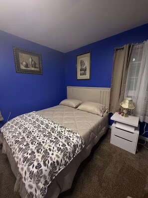 A bedroom with a bed, a bedside table with a lamp, and two framed pictures on the wall. - 3-bedroom house in adorable College Park with AC (College Park)