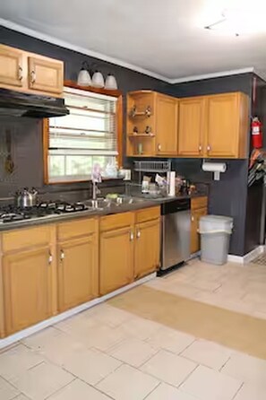A kitchen with wooden cabinets, a stainless steel range, and a window with blinds. - 3-bedroom house in adorable College Park with AC (College Park)