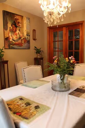 A dining area with a table set for two, a chandelier, and a painting on the wall. - 3-bedroom house in adorable College Park with AC (College Park)