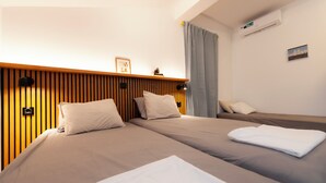 Habitación de hotel con dos camas, cabecera de madera, aire acondicionado montado en la pared y un cuadro enmarcado.