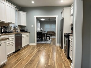 A kitchen with white cabinets, a dishwasher, and a refrigerator. - Dino's Place - Minutes from Downtown Houston. (Houston)