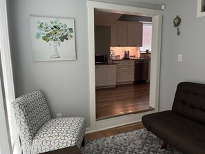 A living room with a patterned armchair, a sofa, and a painting of flowers on the wall. - Dino's Place - Minutes from Downtown Houston. (Houston)