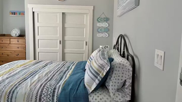 Une chambre à coucher avec un lit, une commode, une porte et une horloge murale.