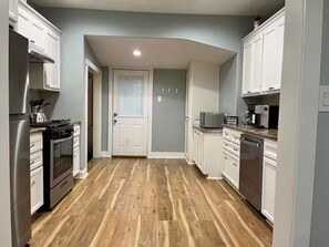 A kitchen with wooden flooring, white cabinets, stainless steel appliances, and a microwave on the countertop. - Dino's Place - Minutes from Downtown Houston. (Houston)