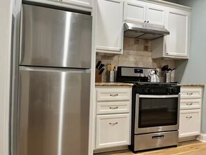 Een keuken met roestvrijstalen apparatuur, witte kasten en een betegelde spatwand.