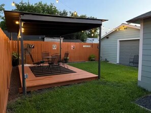 A backyard patio with a wooden deck, metal chairs, and a table. - Dino's Place - Minutes from Downtown Houston. (Houston)