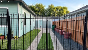 Un lotissement résidentiel fermé, accessible par un chemin qui mène à une maison à la façade bleue.