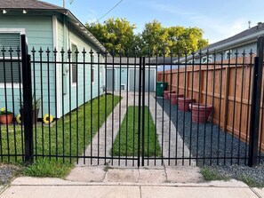 A gated residential area with a pathway leading to a house with a blue exterior. - Dino's Place - Minutes from Downtown Houston. (Houston)