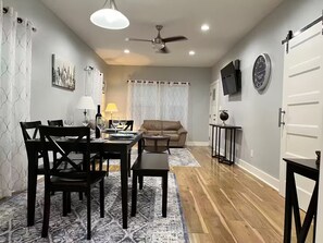 A dining area with a table set for four, a sofa, a small side table, and a ceiling fan. - Dino's Place - Minutes from Downtown Houston. (Houston)