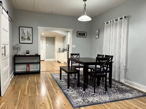 A dining area with a table and chairs, a rug, and a hallway leading to a kitchen. - Dino's Place - Minutes from Downtown Houston. (Houston)