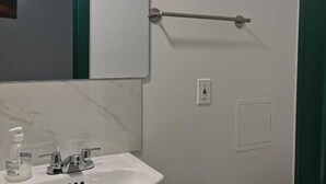 Een badkamer met een witte wasbak, een spiegel, een handdoekhouder en een toilet.