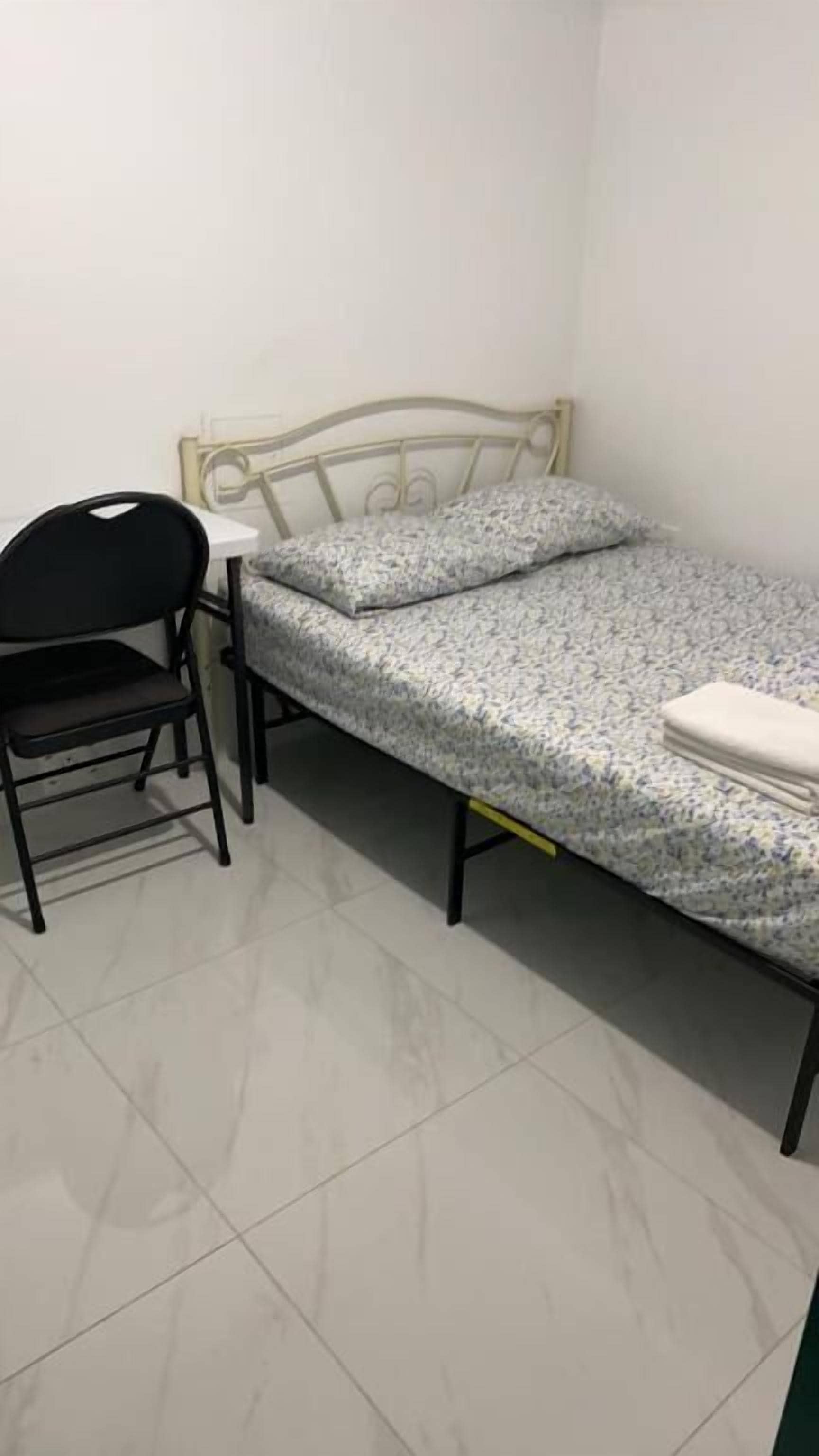 A small room with a bed, a chair, and a desk.