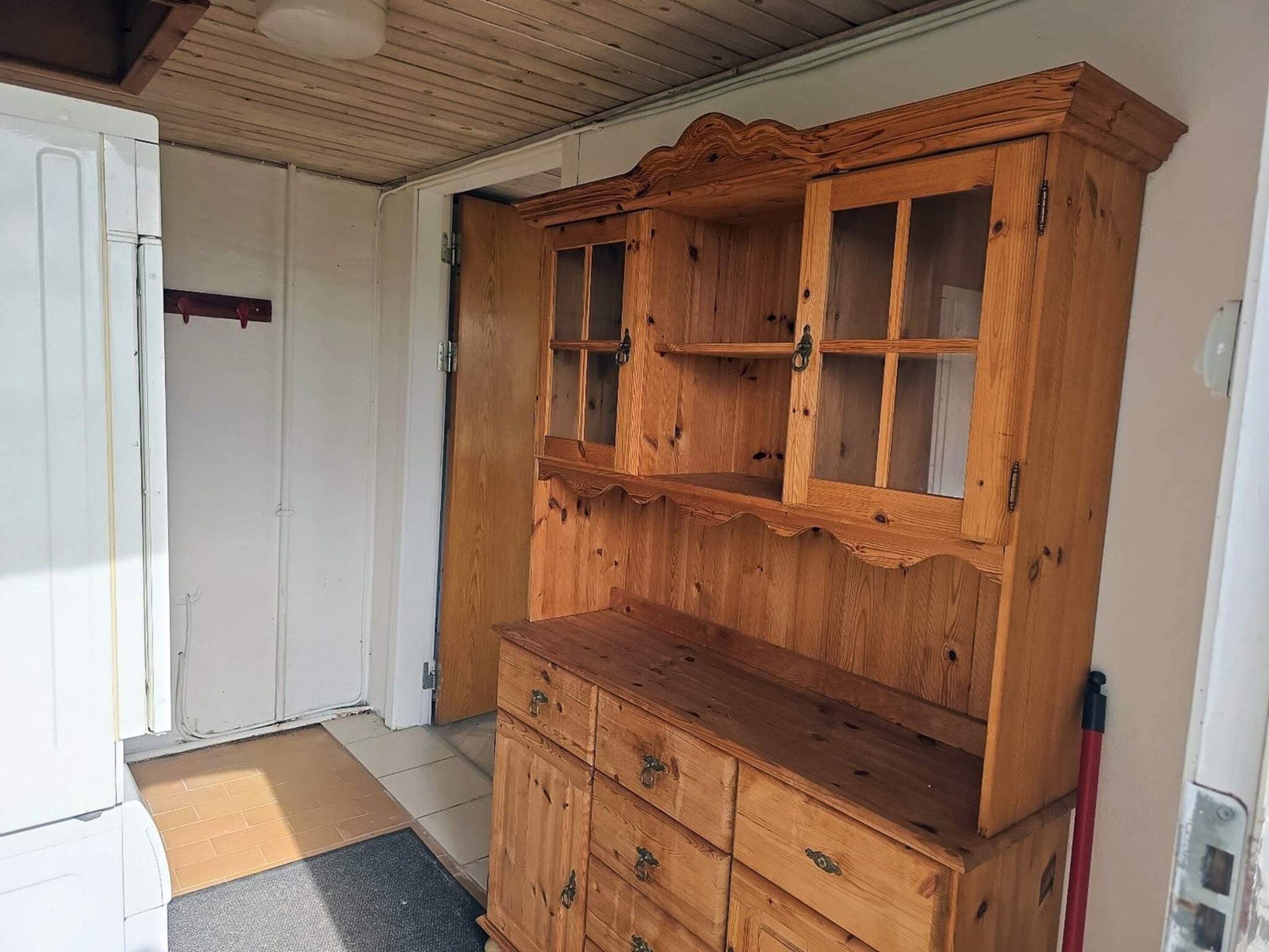 A wooden cabinet with multiple drawers and glass-fronted shelves.