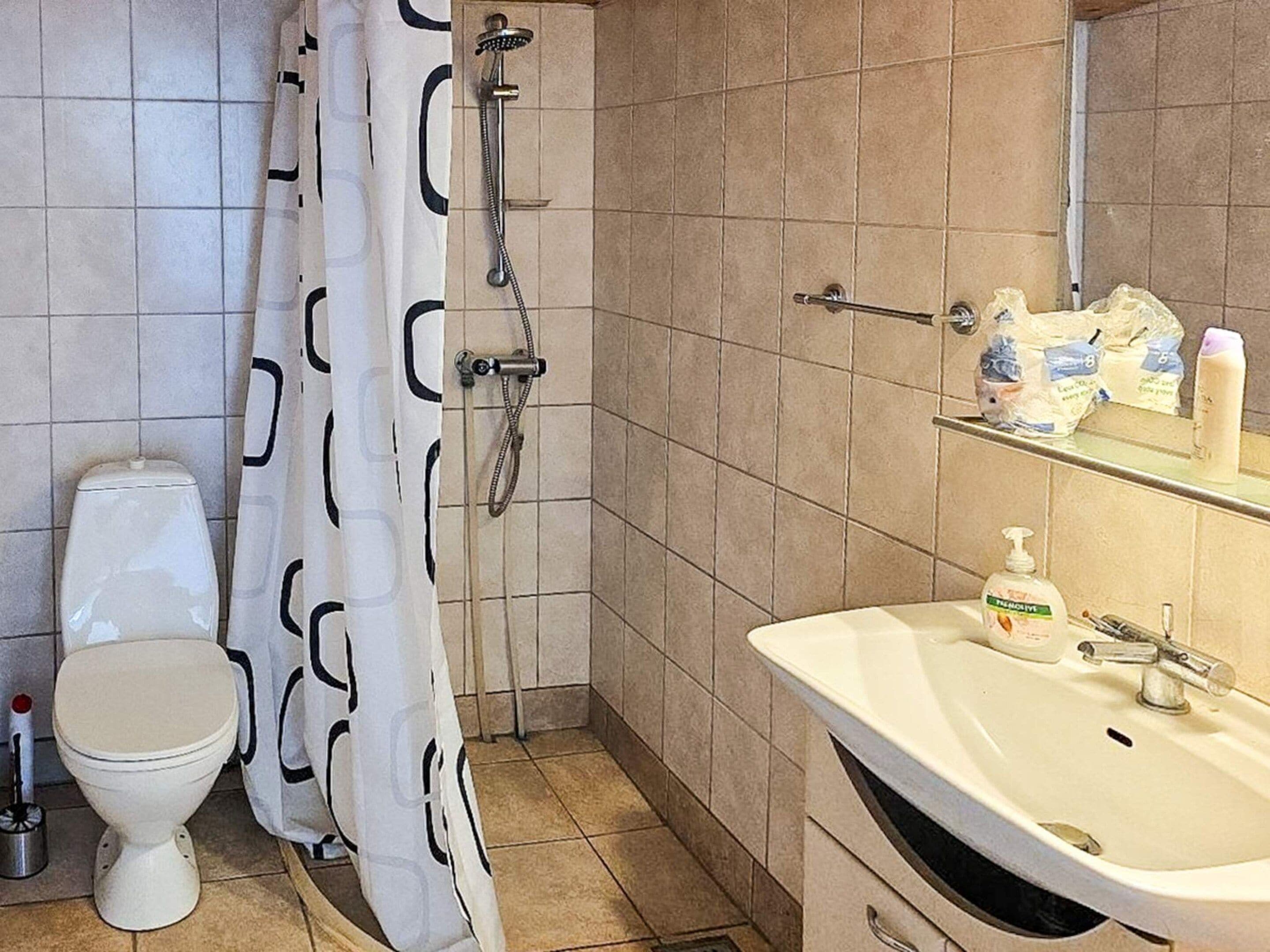 A bathroom with a toilet, shower, and sink.