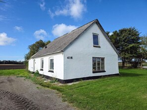 Et hvidt hus med to etager, nummer 416 på siden, en lille veranda og en græsplætte.