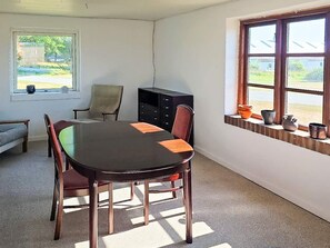 Ein Zimmer mit großem Tisch, Stühlen, einer Couch, einem Schrank und einem Fenster mit Ausblick.