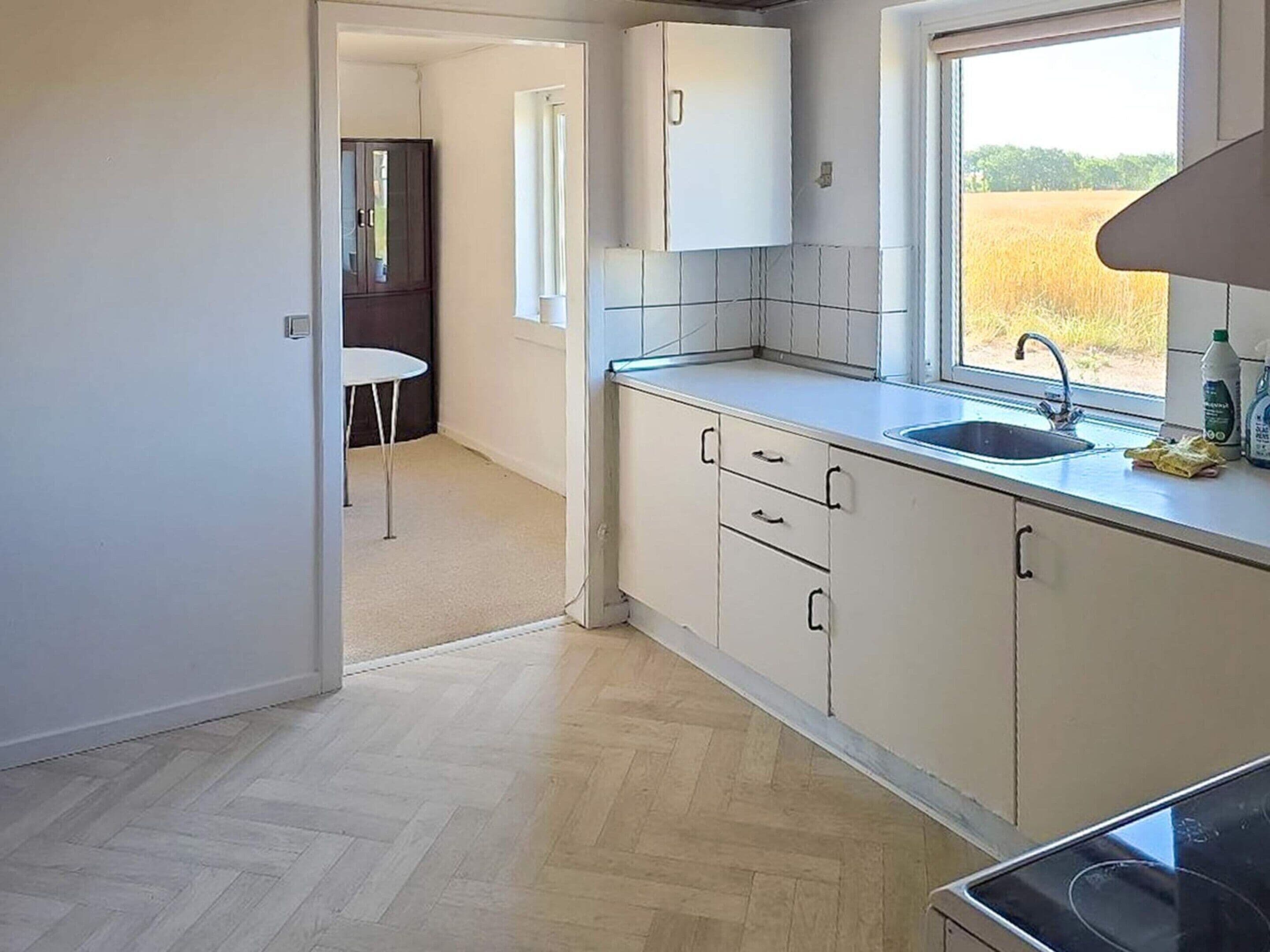 A kitchen with a window, a sink, cabinets, and a stove.