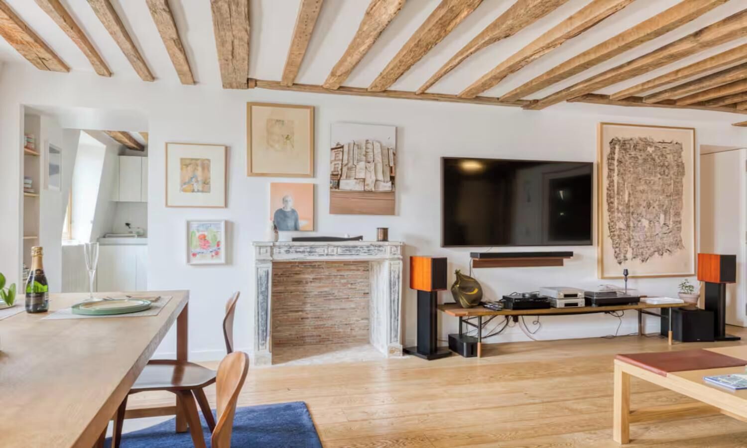 A modern living room with a wooden ceiling, a flat-screen TV, a fireplace, and artwork on the walls.