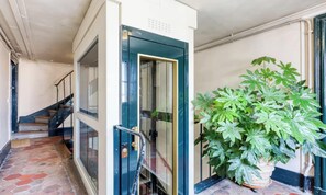 A hallway with a glass door, a staircase, and a potted plant. - A TRULY PARISIAN CHARM – WHERE HISTORY MEET LUXURY – PONT DE ARTS –SAINT GERMAIN (Paris)