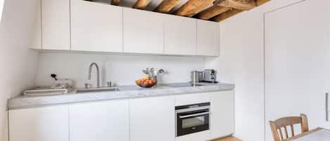 Een moderne keuken met witte kasten, een ingebouwde oven en een marmeren aanrecht.