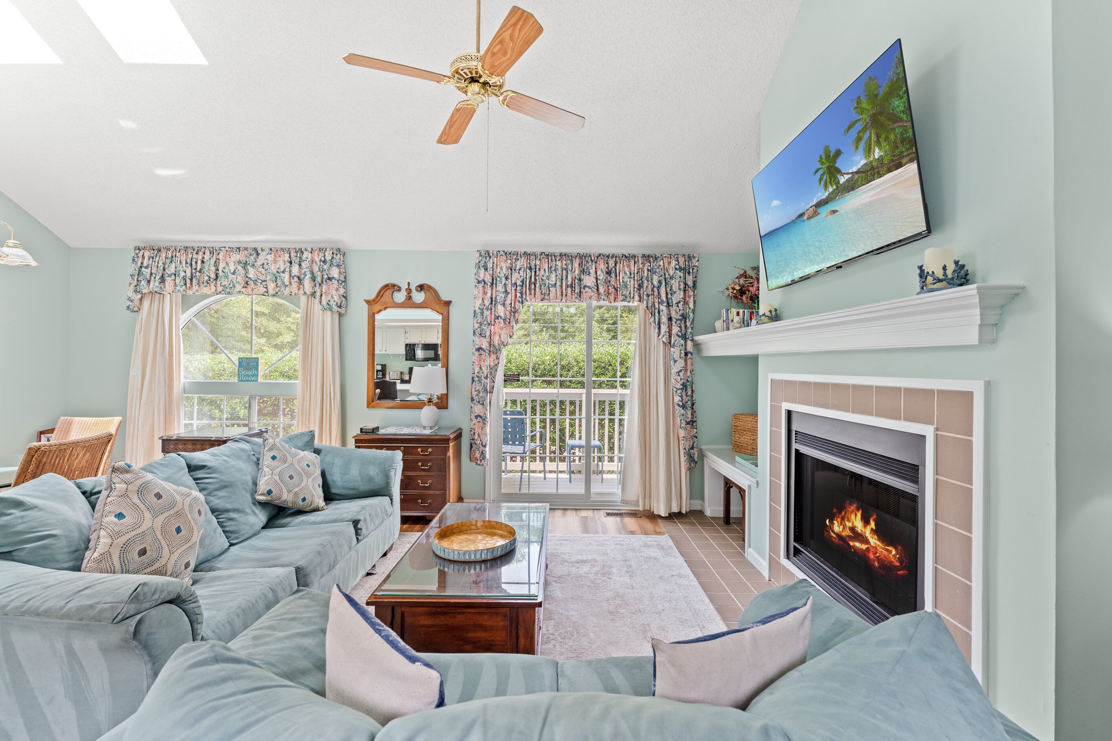 Ein Wohnzimmer mit Sofa, Kamin, Fernseher und Deckenventilator.