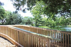 A wooden deck with a curved railing overlooking a body of water, surrounded by trees. - Cumberland Terrace 2E (Myrtle Beach)