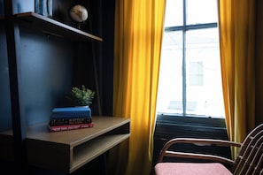 A room with a wooden desk, a globe, and books on it. There is a chair and a window with yellow curtains. - Savannah Home, Walkable to Forsyth, Historic (Savannah)