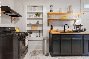 A modern kitchen with a black stove, white cabinetry, and a wooden countertop. - 2 bed/1 bath, Walkable to Forsyth, Historic (Savannah)