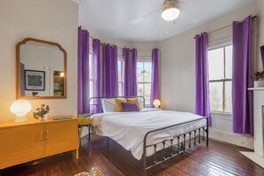 A bedroom with a bed, a nightstand, a dresser, a mirror, and purple curtains. - 2 bed/1 bath, Walkable to Forsyth, Historic (Savannah)