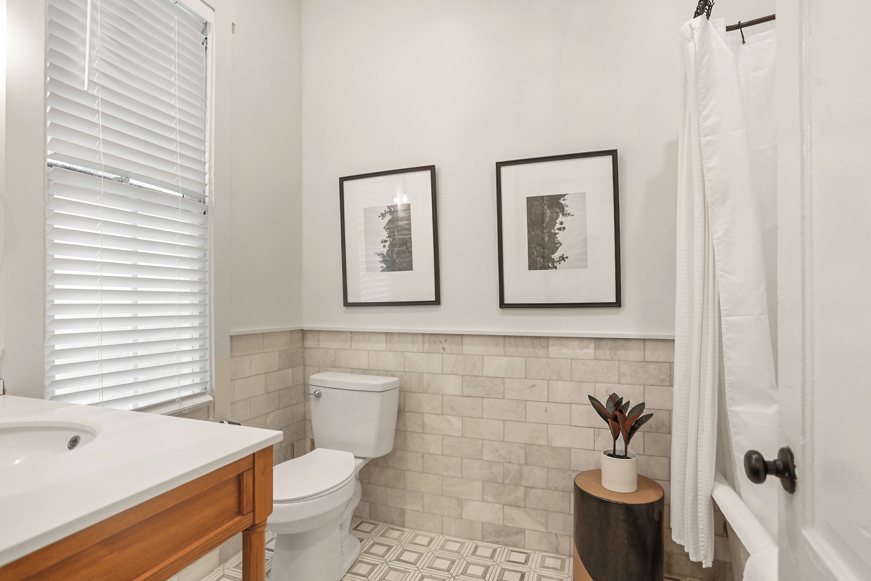 A bathroom with a toilet, sink, and framed pictures on the wall.