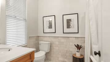 A bathroom with a toilet, sink, and framed pictures on the wall.