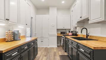 A modern kitchen with white cabinets, black countertops, and a wooden floor.