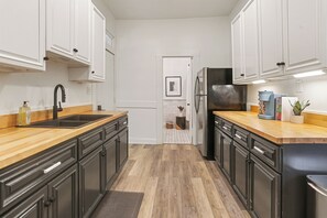 Una cocina con mostradores de madera, gabinetes negros, un refrigerador de acero inoxidable y un lavabo.