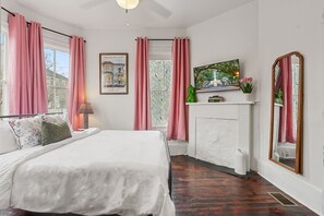 Un dormitorio con cama, chimenea, televisor y espejo.