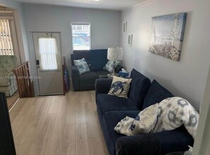 Ein Wohnzimmer mit einem dunkelgrauen Sofa, einer Lampe und einem Gemälde an der Wand.